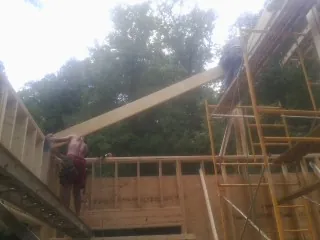 Carpenter raising a rafter beam on a new second story frame in Clear Lake