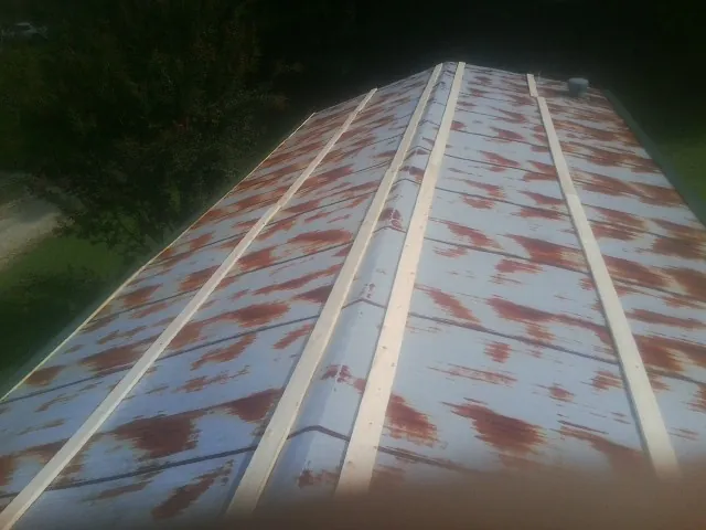 Rusted metal roof panels with new wood purlins before replacement — Storm Damage Roof Repair in Clear Lake by Roofing Brothers