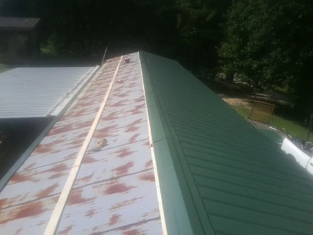 Old rusted panels beside newly installed green metal roofing — Wind Damage Roof Repair by Roofing Brothers in Clear Lake