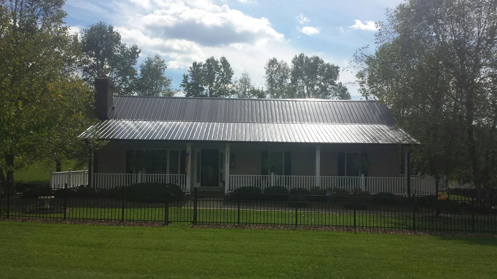 Gray metal roof on a brick ranch with a full width front porch — Gutter Guard Installation work by our crew in Clear Lake