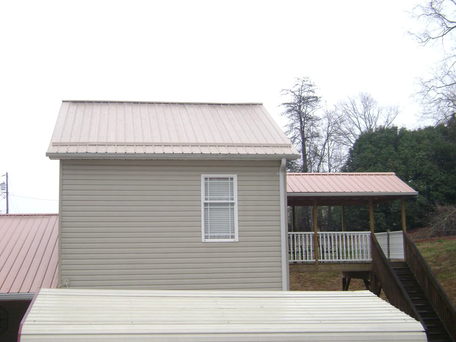 Tan metal roofs on a two story addition and attached porch, from a Roof Replacement job in Clear Lake