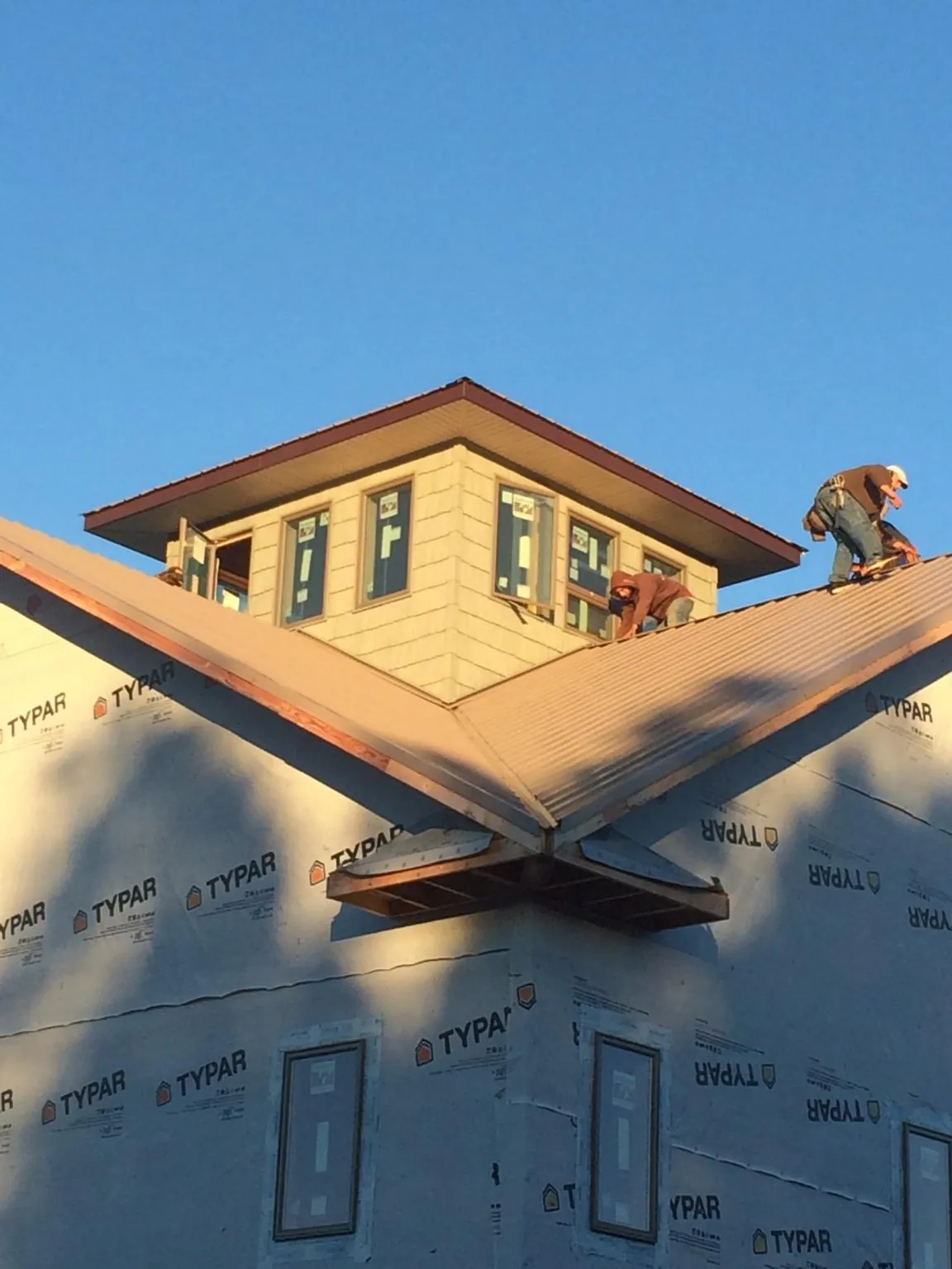 Roofers working around a rooftop cupola on a new metal roof at sunset — Roof Waterproofing in Clear Lake by Roofing Brothers